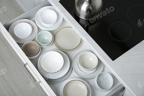 Preview: Open drawer with different plates and bowls in kitchen, above view