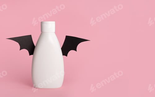 Preview: Mockup of a white bottle with bat wings on a pink background. Halloween concept. Copy space.