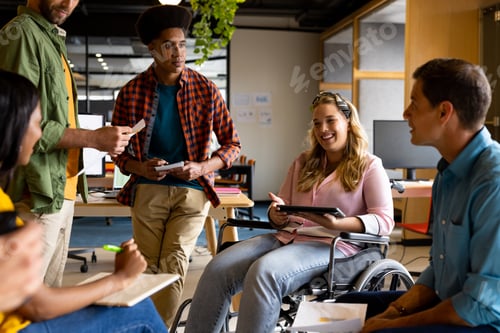 Preview: Happy diverse male and female colleagues in discussion using tablet in casual office meeting