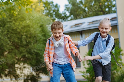 Preview: Happy caucasian children running from school with backpacks on sunny day. Begining of academic year.
