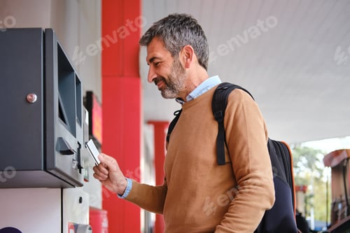 Preview: side view of happy Mature man paying for gas with credit card