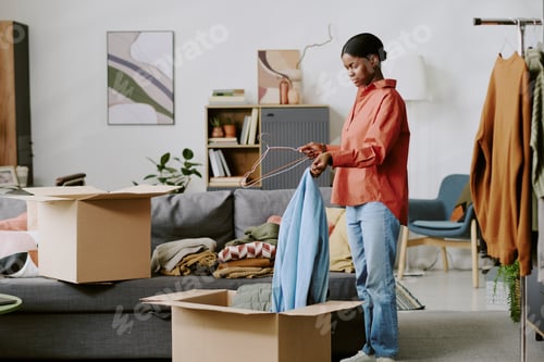 Preview: Black Woman Packing Clothes into Boxes for Home Moving