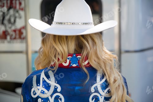 Preview: Rear view of woman with long blond hair wearing white Stetson hat and shiny blue jacket