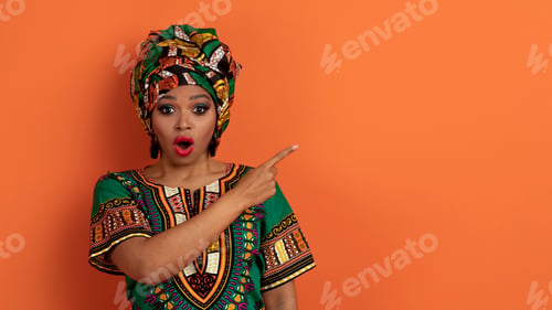 Preview: Shocked black woman in african clothes showing copy space
