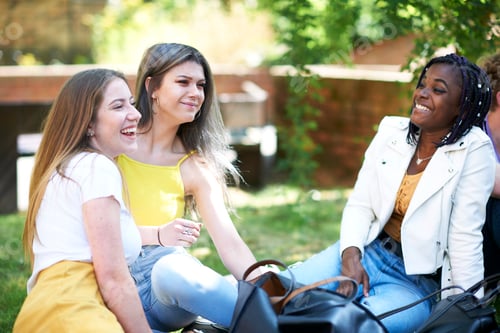 Preview: Female higher education students chatting on college campus lawn
