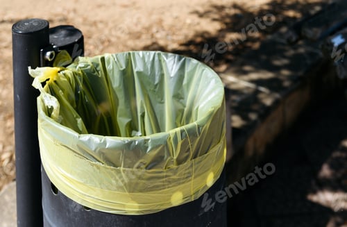 Preview: A Green Trash Bin, Designed with a Yellow Bag, Located in a Beautifully Designed Park Area