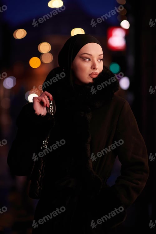 Preview: Muslim woman walking on an urban city street on a cold winter night wearing hijab