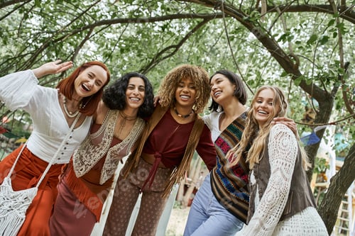 Preview: trendy and interracial group of girlfriends looking at camera outdoors in retreat center