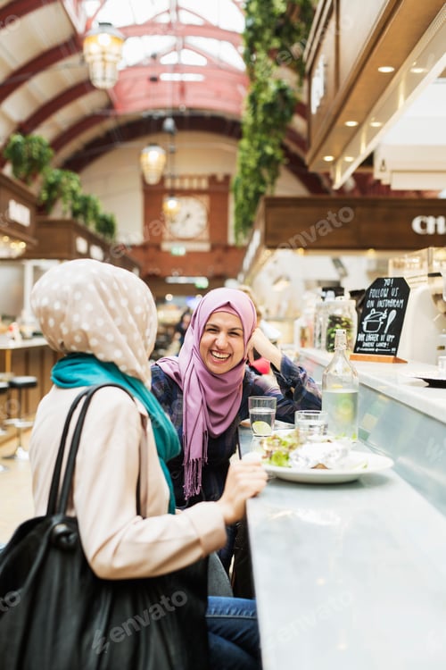 Preview: Happy woman talking to female friend at railroad station cafe