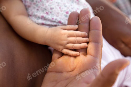 Preview: Father and newborn daughter holding hands at natural light, lifestyle babyhood concept