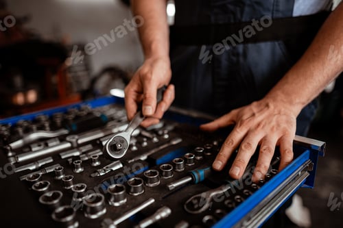 Preview: Mechanic organizes tools in a workshop while preparing for repairs during daytime