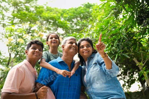 Vista previa: Indian Asian family of four, parents in their forties with two children, in outdoor pointing happily