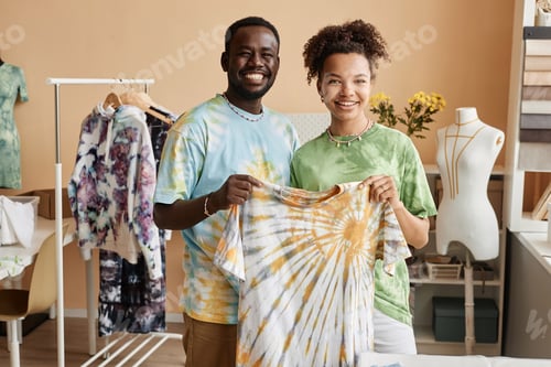 Preview: Two young successful designers holding tie dye t-shirt and looking at camera
