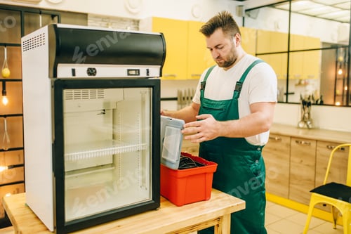 Preview: Worker with toolbox repair refrigerator at home