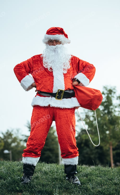 Preview: Santa Claus standing with arms resting on his hips grabbing his red bag. Christmas time