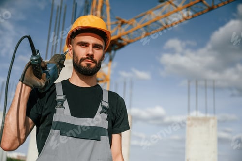Preview: Portrait of man that is in uniform with the drill on the construction site