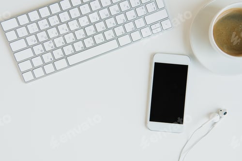 Preview: Top view of keyboard with smartphone and headphones on table top. laptop desk coffee