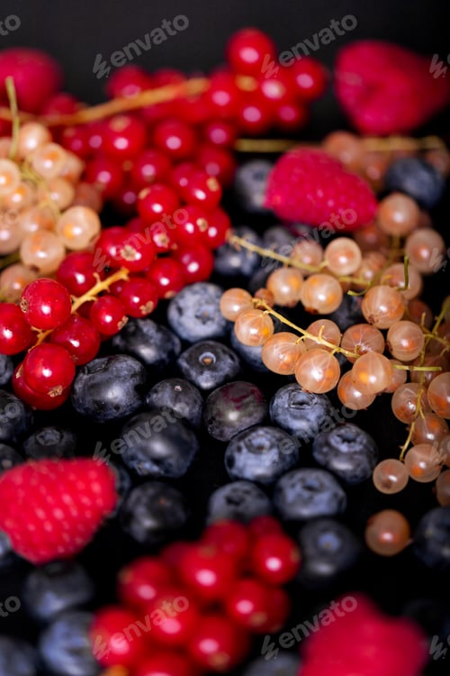 Vista previa: Fresh summer berries in vintage mug over black background, top view