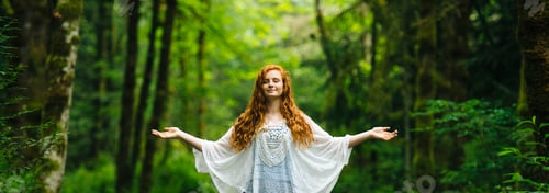 Preview: Panoramic image of young woman meditating with arms open in forest