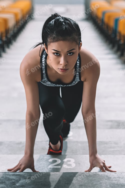 Preview: young asian sportswoman in starting position on stadium stairs, fitness woman running concept