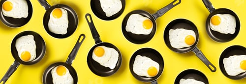 Preview: Creative food pattern with fried eggs on pans over yellow background. Top view. Creative pattern in