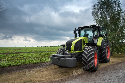 Preview: a new green tractor stands near the field, beautiful sky