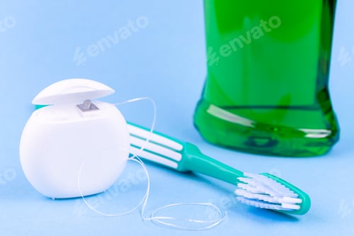 Preview: Tooth care and oral hygiene products. Dental floss, toothbrush and mouthwash on blue background