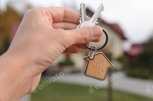 Preview: Woman holding house keys outdoors, closeup. Real estate agent
