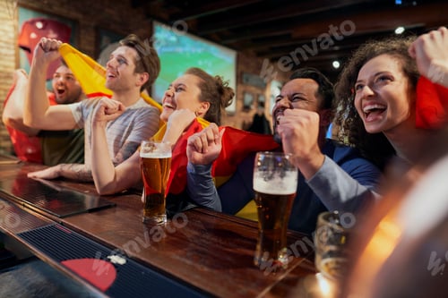 Preview: Group of friends cheering to soccer match in the pub