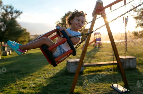 Preview: Portrait of happy little girl on a swing at backlight