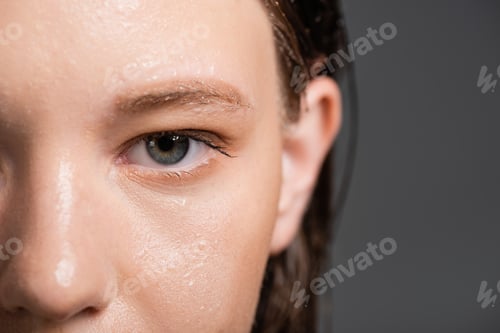 Preview: Cropped view of woman with wet skin and blurred hair looking at camera isolated on grey