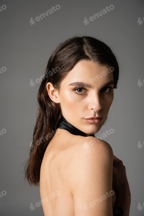 Preview: portrait of sensual and shirtless woman with makeup and piercing looking at camera isolated on grey