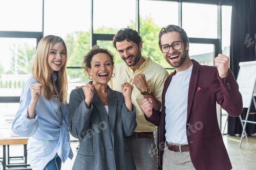 Preview: Excited interracial business people showing yes gesture at camera in office