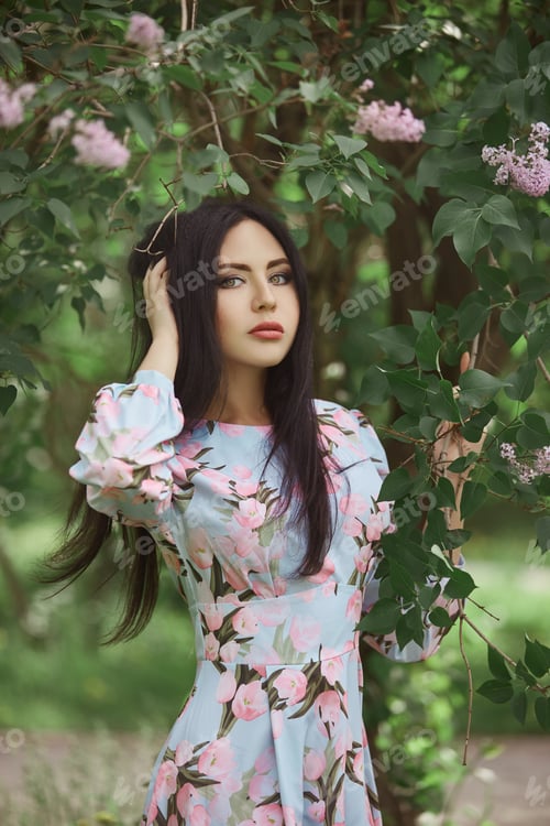 Preview: Brunette woman in the branches of a beautiful flowering tree. Short summer dress