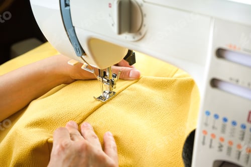 Preview: Female hands stitching yellow fabric on modern sewing machine. Close up view of sewing process.