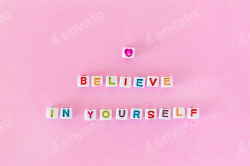 Preview: Quote “Believe in yourself “ made out of beads on pink background