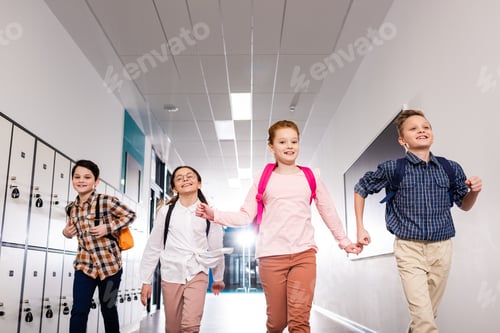Preview: Four excited pupils with backpacks running corridor after lessons