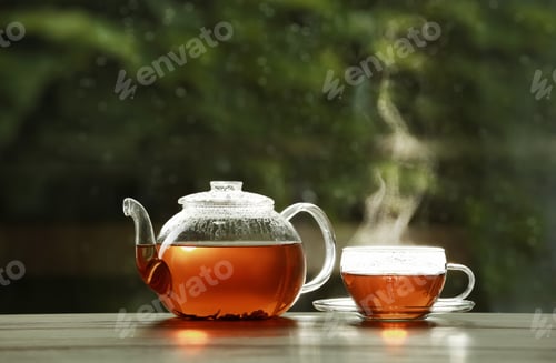 Preview: Teapot and cup of hot tea on wooden table against blurred background, space for text