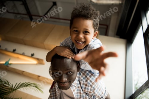 Preview: low angle view of beautiful happy african american father and child hugging and smiling at camera