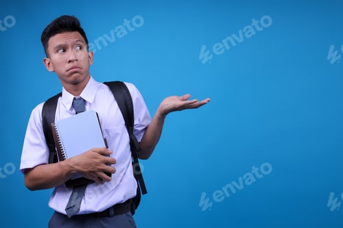 Preview: Young Asian Student Guy Shrugging Hands While Presenting With Copy Space On Blue Background