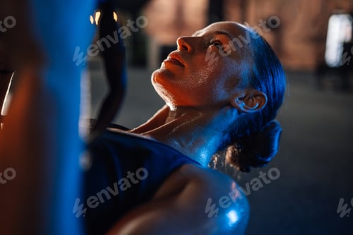 Preview: Young athletic woman is working out with battle ropes in a gym