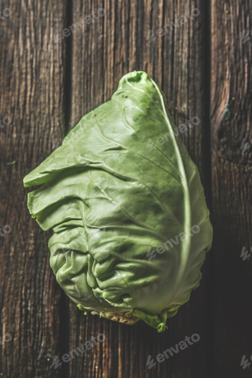 Preview: Close up of raw whole cabbage at rustic brown wooden background. Top view.