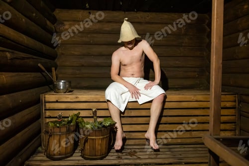 Preview: Man in a wooden Russian bathhouse and buckets with brooms