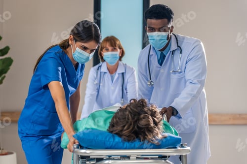 Preview: Group of diverse doctors moving seriously injured patient in hospital.