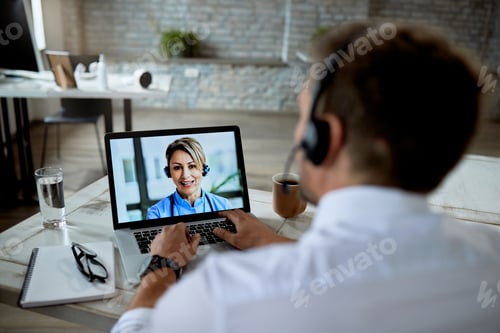 Preview: Close-up of a businessman having video call with a doctor while working in the office.