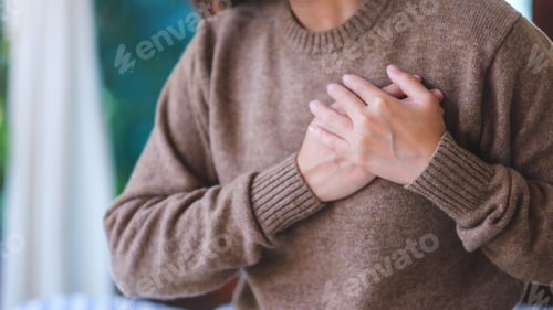 Preview: Closeup image of a woman with hands on chest, sudden heart attack, suffering from chest pain