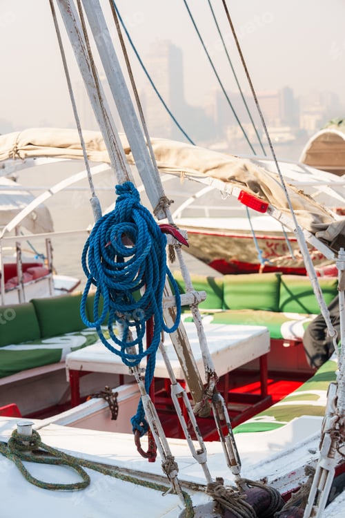 Preview: Nautical preparation with colorful ropes and boats docked in a bustling harbor during a sunny day