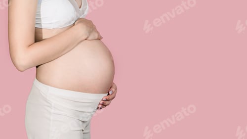 Preview: A young adult pregnant woman in white clothes touches her big naked belly with her hands.Isolated