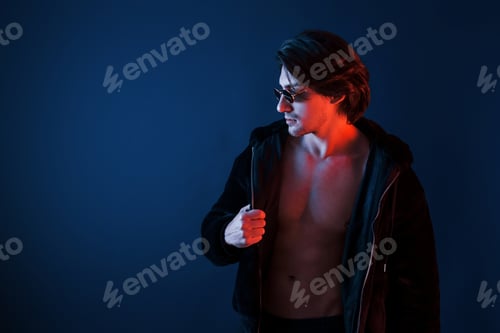 Preview: Beautiful man in glasses and black clothes is in the studio with blue neon lighting