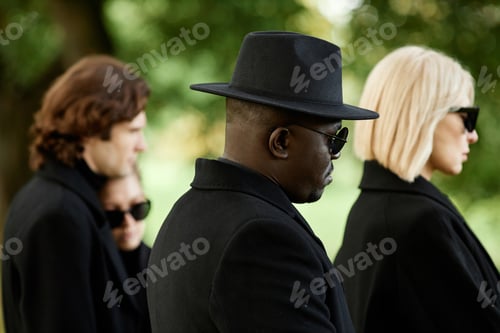 Preview: People wearing all black with sunglasses at outdoor funeral ceremony